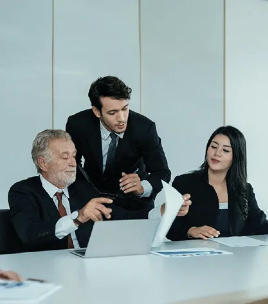 Corporate consulting team discussing business strategy around a conference table with laptop and documents